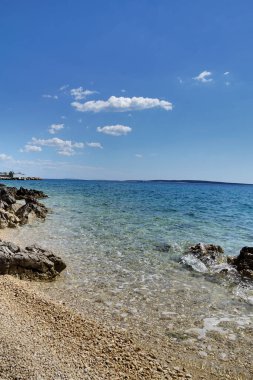 Güzel çakıl taşı plajı ve berrak turkuaz deniz suyu mavi gökyüzünün altında