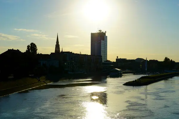 stock image Osijek town building and church silhouette near the Drava river during sunset