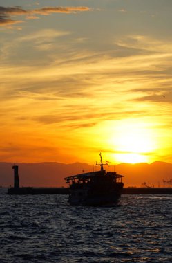 Güneşin önündeki büyük turistik tekne siluetiyle deniz batımı