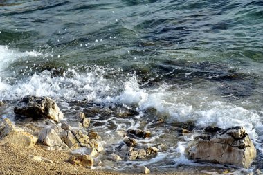 Güney rüzgarı boyunca şeffaf deniz suyu ve sahile yakın uzun dalgalar.