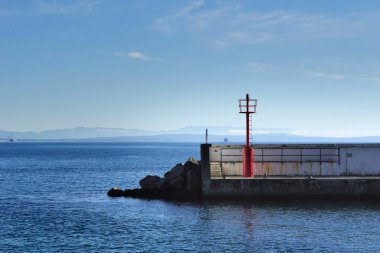Hırvatistan 'daki Opatija Rivierası' nda küçük bir kırmızı metal deniz feneriyle tuğla kırma suyu