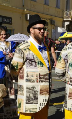 Rijeka, Hırvatistan, 2 Mart 2025. İlginç renkli bir ceketi olan ve kafasında şapkası olan hoş bir genç adam karnavalda eğleniyor.