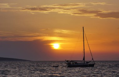 Güzel, sıcak renkler gün batımında denizde, yatın silueti ile birlikte.