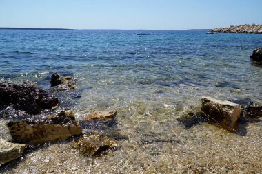 Sıcak yaz gününde, Hırvatistan 'ın Pag Adası' ndaki sahil kıyısında el değmemiş çakıl taşı plajı