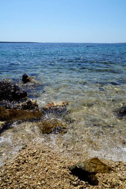 Yaz tatili için mükemmel bir yer olan kayalar ve çakıl taşları arasındaki berrak deniz suyuna giriş