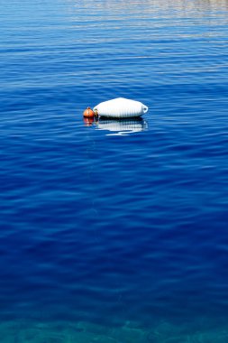 Deniz yüzeyinde yüzen küçük tekneleri bağlamak için beyaz plastik şamandıra.