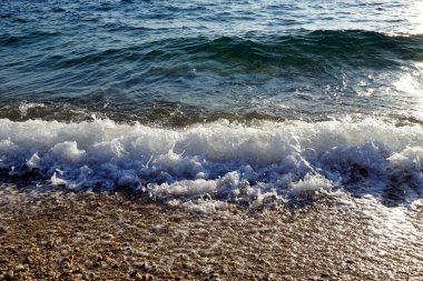 Deniz kıyısındaki güney rüzgarı dalgaları hareket ettiriyor kıyıya çarpan dalgalar ve çakıl taşı plajı