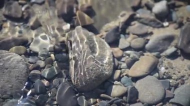 Texture shadows on the stones through the clear water of a mountain river