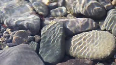 Texture shadows on the stones through the clear water of a mountain river