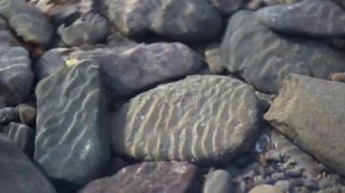Texture shadows on the stones through the clear water of a mountain river