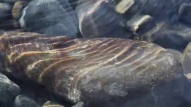 Texture shadows on the stones through the clear water of a mountain river