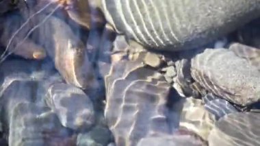 Texture shadows on the stones through the clear water of a mountain river