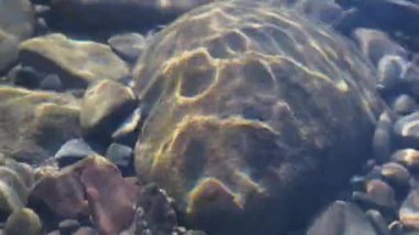 Texture shadows on the stones through the clear water of a mountain river