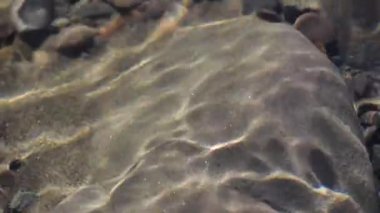 Texture shadows on the stones through the clear water of a mountain river