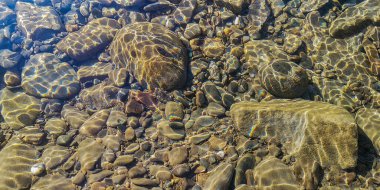 Texture shadows on the stones through the clear water of a mountain river