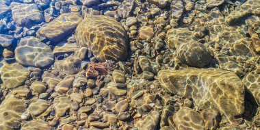 Texture shadows on the stones through the clear water of a mountain river