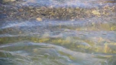 Texture shadows on the stones through the clear water of a mountain river