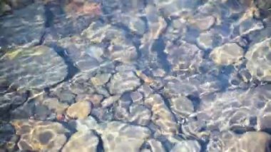 Texture shadows on the stones through the clear water of a mountain river