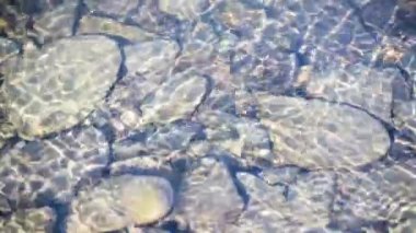 Texture shadows on the stones through the clear water of a mountain river
