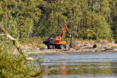 Bir kazıcı bir kamyonu taşlarla doldurur.