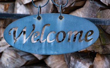 Odunların dizildiği bir arka planda hoş geldiniz işareti