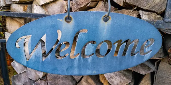 Odunların dizildiği bir arka planda hoş geldiniz işareti