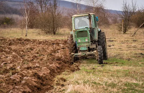 Eski bir traktör kırsal bir dağlık alanda toprağı sürüyor.