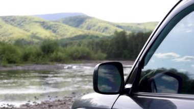 Güneşli bir günde bir dağ nehrinde SUV.