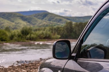 Güneşli bir günde bir dağ nehrinde SUV.