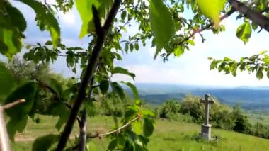 Dağdaki bir köyde tapınma haçı olan bir manzara.