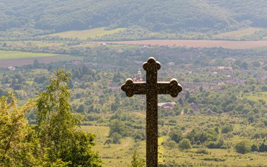 Dağdaki bir köyde tapınma haçı olan bir manzara.