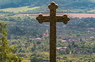 Dağdaki bir köyde tapınma haçı olan bir manzara.