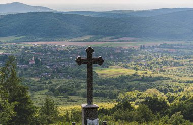 Dağdaki bir köyde tapınma haçı olan bir manzara.