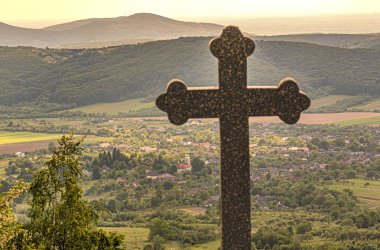 Dağdaki bir köyde tapınma haçı olan bir manzara.