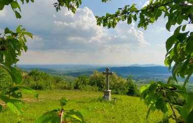 Dağdaki bir köyde tapınma haçı olan bir manzara.