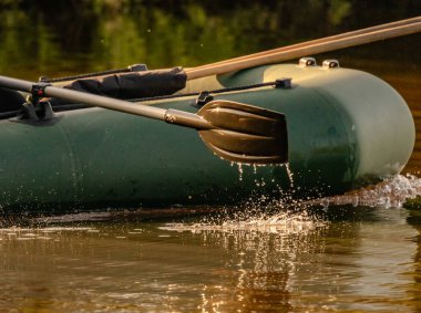Lastik bir teknenin küreğinden su akar.