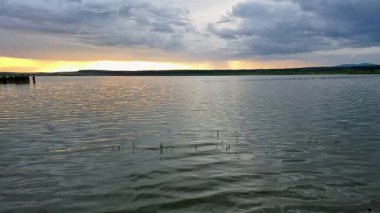 Yazın gün batımında fırtınadan önceki bir göl manzarası.