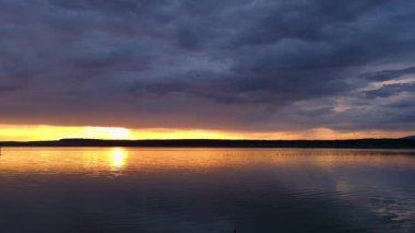 Yazın gün batımında fırtınadan önceki bir göl manzarası.