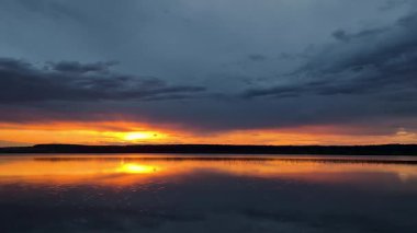 Yazın gün batımında fırtınadan önceki bir göl manzarası.