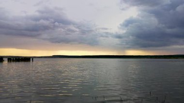 Yazın gün batımında fırtınadan önceki bir göl manzarası.