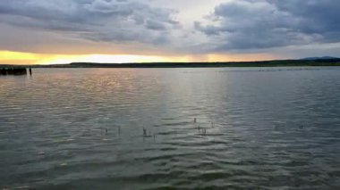 Gün batımında fırtınadan önce bir göl manzarasının zamanaşımı