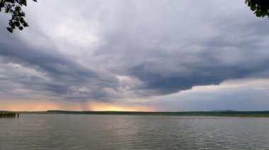 Gün batımında fırtınadan önce bir göl manzarasının zamanaşımı