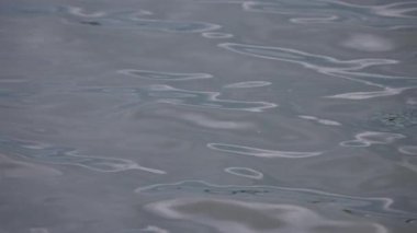 Gökyüzü yansıması ve günbatımı renkleriyle desenli göl dalgaları