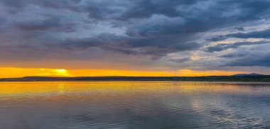 Yazın gün batımında fırtınadan önceki bir göl manzarası.