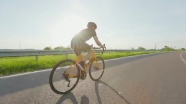 Spor giyimli, kasklı ve güneş gözlüklü profesyonel bir motosikletçi asfalt yolda güzel yeşil doğanın arasında sürüyor. Spor ve eğitim anlayışı.