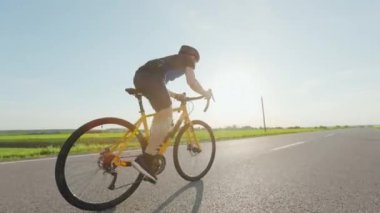 Siyah spor kıyafetli profesyonel bisikletçi ve karayolu boyunca yol bisikleti üzerinde güvenlik miğferi eğitimi. Motivasyonu, dayanıklılığı ve insanları kavrayın.