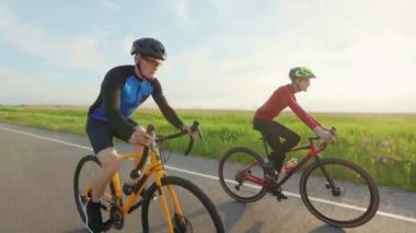 Genç beyaz adamlar, kır yolunda yoğun eğitim sırasında yarış bisikletlerine sert pedallar basıyorlar. Etkin yaşam tarzları ve fitness egzersizleri kavramı.