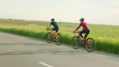 Spor giyim ve kask giyen, açık havada bisiklet sürmek için zaman harcayan, arka planda yeşil yaz tarlası olan Kafkas erkekleri. İnsan kavramı ve egzersiz.