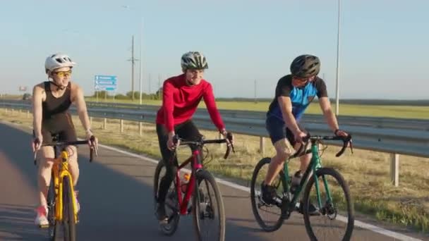 快乐的高加索男女朋友穿着运动服 戴着安全帽骑自行车在柏油路上 骑单车人士一起在户外消闲时间 — 图库视频影像