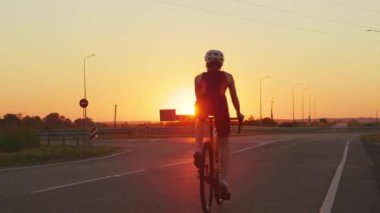 Spor elbiseli, kasklı ve gözlüklü beyaz arkadaşlar dışarıda bisiklet sürerken eğleniyorlar. Arka planda güzel bir yaz günbatımı. Gençler için aktif hobi.
